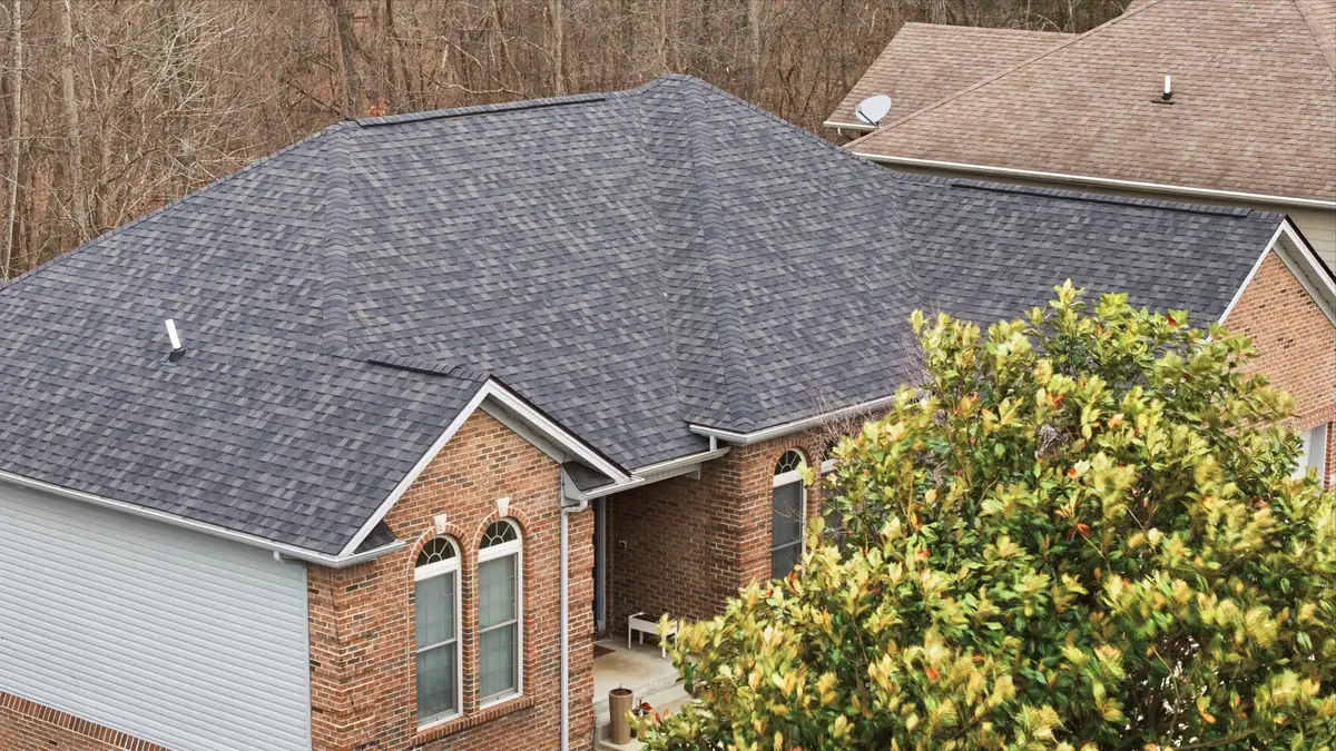 Brick home with a charcoal hip roof beside a large magnolia