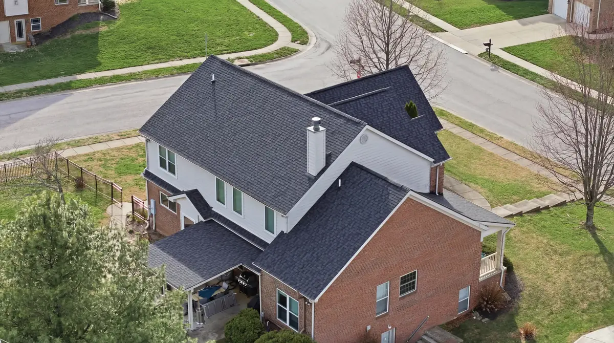 Aerial of a brick and siding two story with a new charcoal roof and white chimney