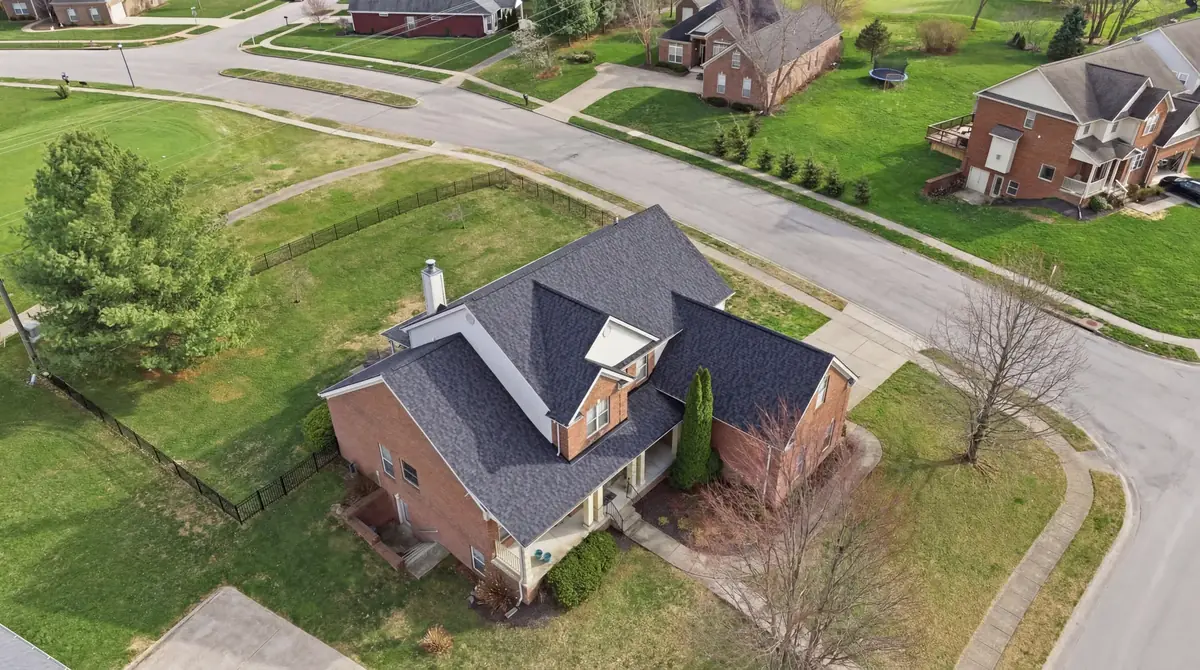 Aerial of a brick two story on a corner lot with a dark shingle roof