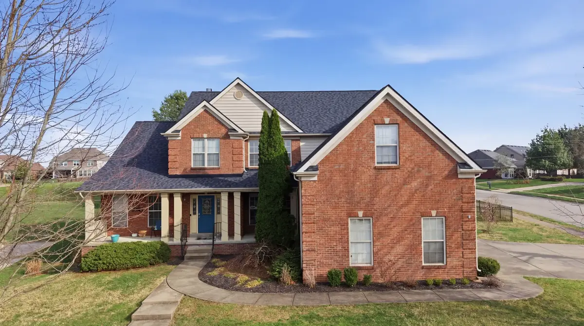 Ground level front view of a brick two story with a new dark shingle roof and blue front door