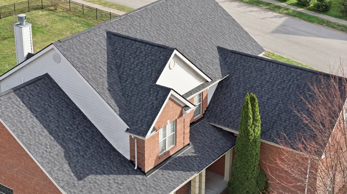 Close aerial of charcoal architectural shingles around a brick dormer