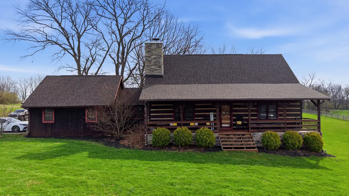 Log home with a dark shingle roof and a brick chimney