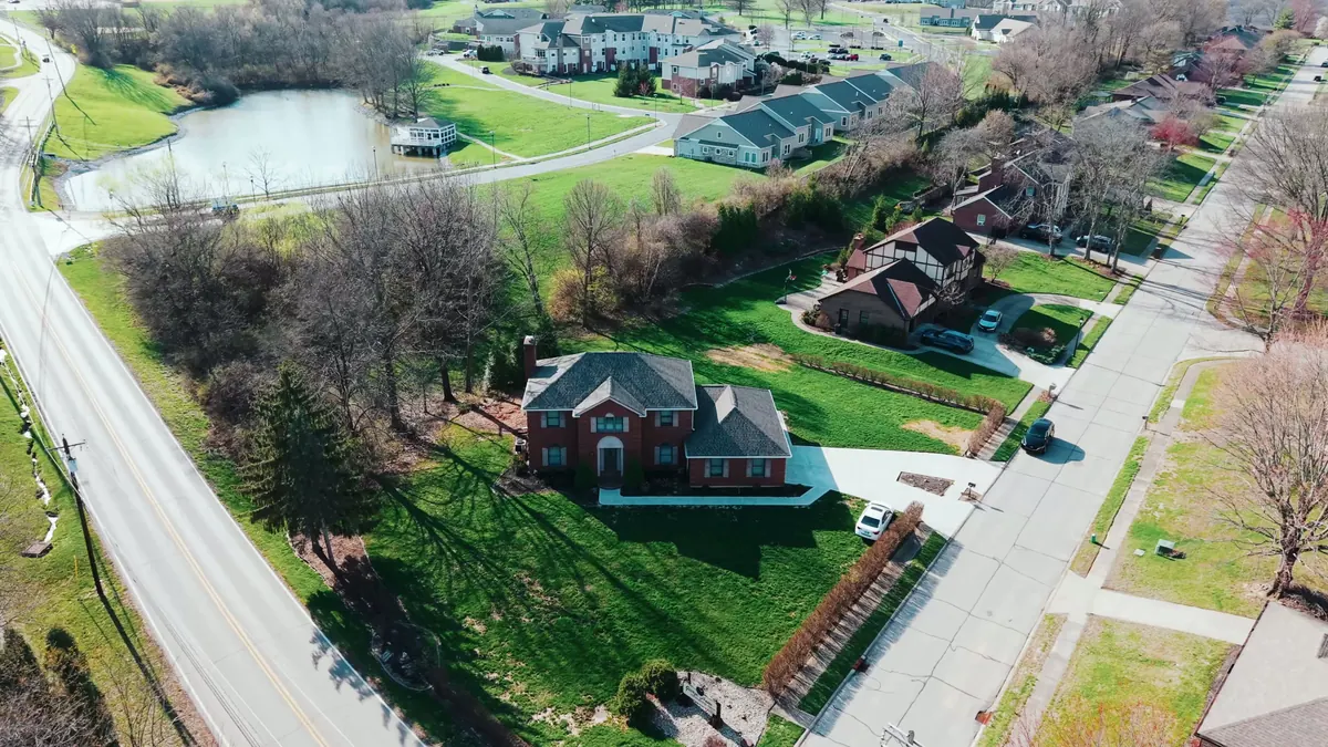 Aerial view of a brick home with a new roof on a wide green lot