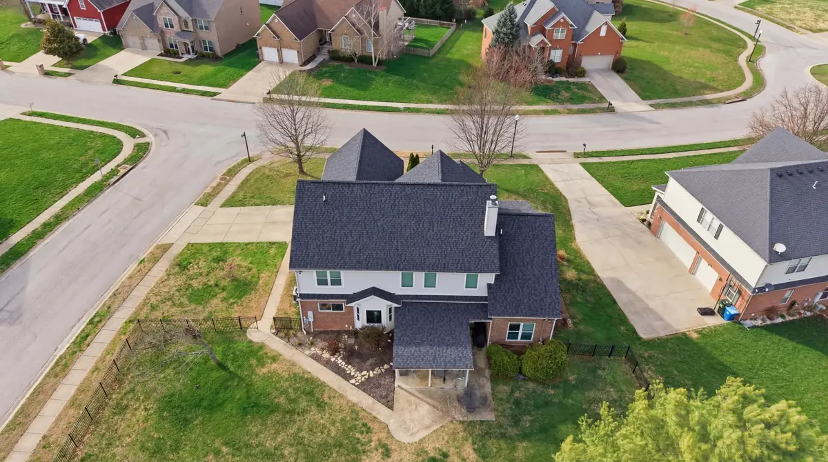 Aerial of a two story home with green shutters and a new dark shingle roof