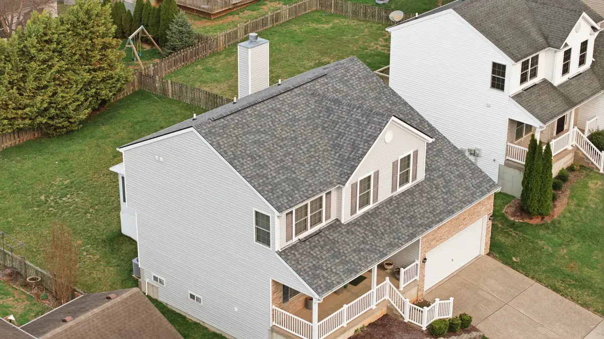 Aerial of a white sided home with a new grey shingle roof and front porch